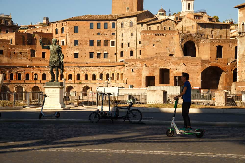 man on electric scooter between roman monuments, source: Shutterstock
