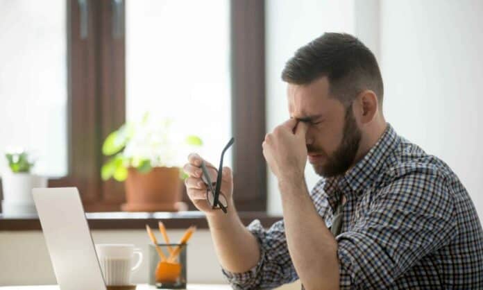 Stressed male massaging nose bridge suffering from headache Tired office worker