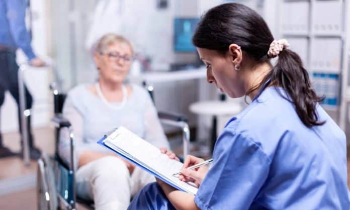 Nurse writing on clipboard Νοσοκόμα και ηλικιωμένη ασθενής σε αμαξίδιο