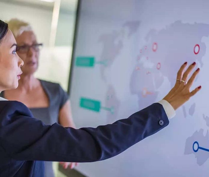 Coface, women looking at world map on screen