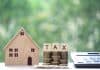 Property tax concept, model house with stack of coins and calculator, source: Shutterstock