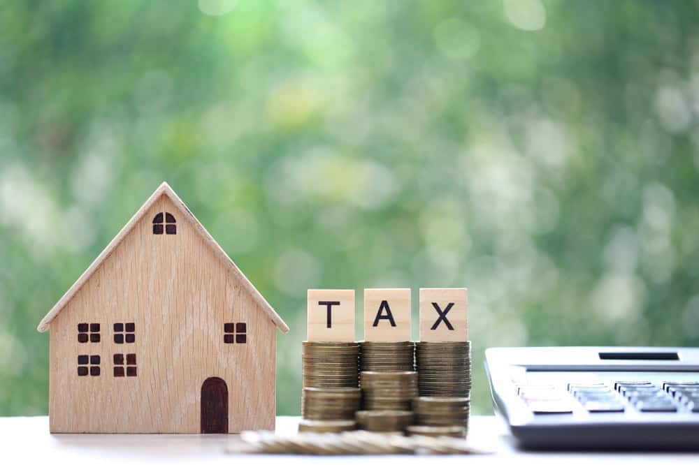 Property tax concept, model house with stack of coins and calculator, source: Shutterstock
