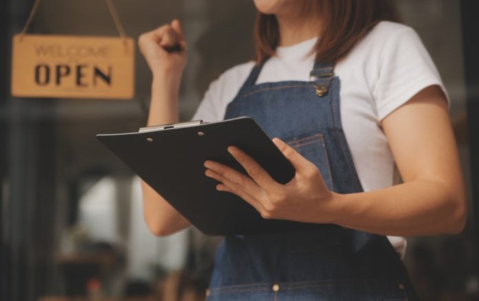 Young small business owner in front of open shop, source: Shutterstock
