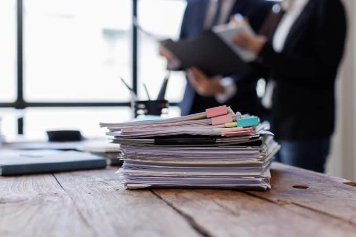 Στοίβα εγγράφων σε γραφείο, στελέχη στο βάθος, πηγή: EIOPA / Adobe Stock