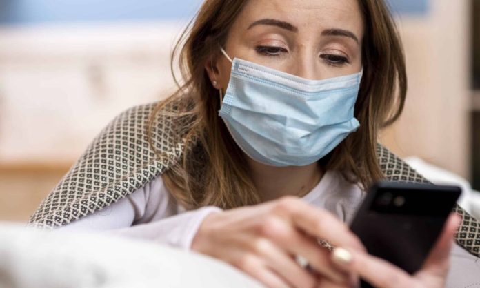 Ασθενής με μάσκα και κινητό τηλέφωνο