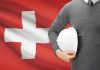 Swiss health insurance benefit conept, with flag and employee with helmet, source: Shutterstock
