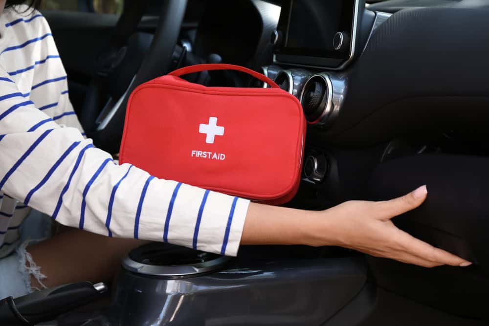 Woman driver holding first aid kit, source: Shutterstock