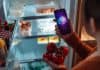 EY, AI report cover image, woman with smartphone and tomatoes standing at the fridge