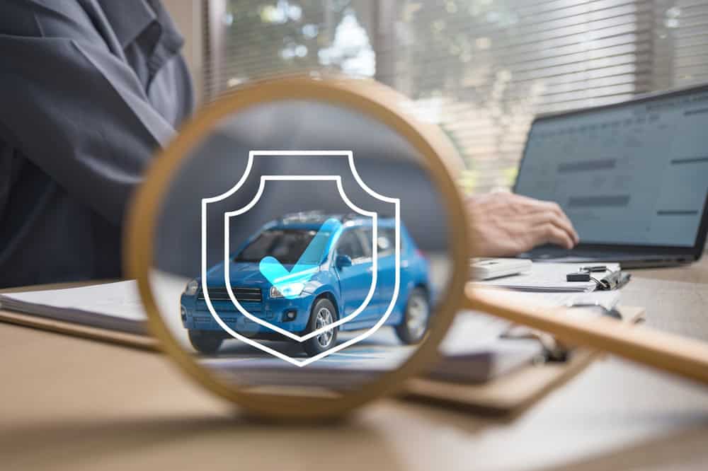 Car safety concept, man at laptop and blue car with insurance sign and magnifying glass, source: Shutterstock